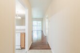 This single-floor residence offers a well-organized layout with a variety of functional spaces connected by a tiled entry hallway, which also houses the electrical panel. The hallway leads toward the main living area, where rich hardwood flooring extends throughout and a sliding glass door opens to a private balcony, filling the space with natural light and outdoor views of surrounding greenery.

The kitchen is designed for practicality and efficiency, featuring warm oak cabinetry that extends to the upper and lower levels, light-toned countertops, a double stainless steel sink, and white appliances including an electric range, over-the-range microwave, refrigerator, and dishwasher. A skylight adds brightness overhead. The kitchen connects seamlessly to the living and dining area via a pass-through counter, creating an open and sociable flow. The dining area is accented by an elegant chandelier.

The bedrooms are carpeted and offer a quiet, comfortable atmosphere, each with windows that frame lush outdoor views. The bathroom is cleanly appointed with a vanity featuring oak cabinetry, a large mirror with overhead lighting, a tub-shower combination, and tile flooring. Textured ceilings are present throughout, adding a consistent architectural detail across the entire space.