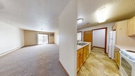 Located at 1115 41st St NW in Rochester, Minnesota, this one-bedroom, one-bathroom unit offers a thoughtfully arranged single-floor layout. The open-concept kitchen serves as a central hub, featuring light maple cabinetry, ample counter space, a double-basin sink set into a peninsula, and white appliances including a coil-top electric range, over-the-range microwave, and refrigerator. Tile flooring runs throughout the kitchen, providing a clean and durable surface. The living area is generously sized with plush carpeting and a textured ceiling, and is bathed in natural light through a sliding glass door that opens to a private balcony. The bedroom offers comfortable proportions with carpeted flooring, a window framing outdoor views, and baseboard heating. A standout feature of the bedroom area is the dual closets with wire shelving systems, delivering excellent storage capacity. The full bathroom is finished with tile flooring, a single-sink vanity with maple cabinetry, a large mirror, and a grab bar for added convenience. Warm wood trim accents are carried consistently throughout the unit, tying the interior together with a cohesive, classic aesthetic.