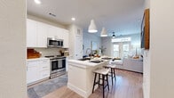 This thoughtfully designed one-bedroom, one-bathroom residence offers a cohesive open-concept layout that maximizes every square foot. Light wood-tone flooring runs throughout the main living areas, complementing a bright, neutral color palette that creates a clean and airy atmosphere.

The kitchen is a standout feature, showcasing white shaker cabinetry, subway tile backsplash, a full suite of stainless steel appliances, and a central island with an undermount sink and bar seating — perfect for casual dining. Elegant pendant lighting overhead adds a refined touch. The kitchen flows seamlessly into the living room, where a ceiling fan, recessed lighting, and French doors open to a private balcony that brings in abundant natural light and outdoor views.

The hallway entry is welcoming and well-proportioned, providing a graceful transition into the main living spaces. The bedroom offers plush carpeting, large windows with ample natural light, and a serene, restful ambiance. The full bathroom is generously sized, featuring white shaker vanity cabinetry, a wide countertop with an undermount sink, a large framed mirror, and a full tub-shower combination with white tile surround. Clean lines and neutral tones carry throughout, lending the entire space a modern yet comfortable character.