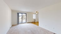 This single-floor unit is laid out to maximize functionality across its well-defined living spaces. The main living area is generously proportioned, featuring neutral wall-to-wall carpeting, a ceiling fan with light fixture, and a large sliding glass door that opens onto a private balcony overlooking mature trees and the surrounding landscape. Baseboard heating and a wall-mounted air conditioning unit ensure year-round comfort. The living space connects seamlessly to a dedicated dining area, finished with classic parquet flooring that extends into the adjacent galley-style kitchen.

The kitchen is efficiently arranged with white cabinetry featuring wood-trimmed accents, a stainless steel sink, a white electric coil-burner range, a dishwasher, and ample counter space. A window and ceiling fan keep the area bright and ventilated.

The unit includes two carpeted bedrooms, each offering a quiet retreat with natural light from windows fitted with blinds. One bedroom provides closet storage, while both rooms benefit from baseboard heating and wall AC units. The full bathroom features a tiled tub-shower combination with chrome fixtures and a clean, neutral finish throughout.