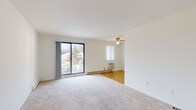 This single-floor unit is laid out to maximize functionality across its well-defined living spaces. The main living area is generously proportioned, featuring neutral wall-to-wall carpeting, a ceiling fan with light fixture, and a large sliding glass door that opens onto a private balcony overlooking mature trees and the surrounding landscape. Baseboard heating and a wall-mounted air conditioning unit ensure year-round comfort. The living space connects seamlessly to a dedicated dining area, finished with classic parquet flooring that extends into the adjacent galley-style kitchen.

The kitchen is efficiently arranged with white cabinetry featuring wood-trimmed accents, a stainless steel sink, a white electric coil-burner range, a dishwasher, and ample counter space. A window and ceiling fan keep the area bright and ventilated.

The unit includes two carpeted bedrooms, each offering a quiet retreat with natural light from windows fitted with blinds. One bedroom provides closet storage, while both rooms benefit from baseboard heating and wall AC units. The full bathroom features a tiled tub-shower combination with chrome fixtures and a clean, neutral finish throughout.