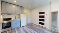Located at 147 W Richmond Ave in Richmond, CA, this one-bedroom, one-bathroom unit offers a thoughtfully designed layout that makes efficient use of its compact footprint. The combined kitchen and living area serves as the heart of the space, featuring light gray shaker-style cabinetry, a stainless steel range, a full-size refrigerator, and a single-basin sink — all set against clean white walls and recessed lighting. Light-toned hardwood-style flooring runs consistently throughout, lending a sense of continuity and warmth. A striking exposed brick wall adds significant character to both the living area and the bedroom, blending industrial charm with the unit's otherwise clean, contemporary aesthetic. The bedroom is a well-proportioned private retreat, brightened by a window that allows natural light to filter in alongside views of the brick accent wall. A dedicated closet provides practical storage. The modern bathroom is finished with large-format tile flooring, a wall-mounted vanity with an integrated sink, a framed mirror with overhead lighting, and a glass-enclosed shower. A stylish four-panel entry door with dark glass inserts completes the unit's updated, design-forward feel.