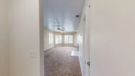 This single-story unit at 1960 Oak Twist Ct in Bellair, Florida offers a practical and comfortable layout across two bedrooms, one bathroom, a living room, kitchen, hallway, and closet. The living room is the centerpiece of the home, featuring warm neutral-toned carpet, a ceiling fan with light fixture, textured ceiling, and a bank of windows that allow generous natural light to fill the space. The open sightline into the kitchen enhances the sense of roominess. The kitchen is galley-style and well-appointed with warm wood cabinetry, dark countertops, tile flooring, a double-basin sink, and white appliances including a range and refrigerator. Both bedrooms are carpeted with textured ceilings and neutral walls; the primary bedroom offers dual windows with outdoor views, while the secondary bedroom includes a single window. The full bathroom features tile flooring, a tiled tub-and-shower combination, and clean white fixtures. A dedicated closet and multiple hallways provide practical storage throughout. The unit maintains a consistent neutral palette, creating a cohesive and move-in ready environment.