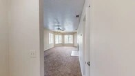This single-story unit at 1960 Oak Twist Ct in Bellair, Florida offers a practical and comfortable layout across two bedrooms, one bathroom, a living room, kitchen, hallway, and closet. The living room is the centerpiece of the home, featuring warm neutral-toned carpet, a ceiling fan with light fixture, textured ceiling, and a bank of windows that allow generous natural light to fill the space. The open sightline into the kitchen enhances the sense of roominess. The kitchen is galley-style and well-appointed with warm wood cabinetry, dark countertops, tile flooring, a double-basin sink, and white appliances including a range and refrigerator. Both bedrooms are carpeted with textured ceilings and neutral walls; the primary bedroom offers dual windows with outdoor views, while the secondary bedroom includes a single window. The full bathroom features tile flooring, a tiled tub-and-shower combination, and clean white fixtures. A dedicated closet and multiple hallways provide practical storage throughout. The unit maintains a consistent neutral palette, creating a cohesive and move-in ready environment.