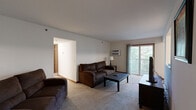 This single-floor home in Allegan, Michigan offers a practical and comfortable layout across three bedrooms and two bathrooms. The carpeted living room serves as the central gathering space, featuring a wall-mounted air conditioning unit and a sliding glass door that opens to a balcony overlooking lush, tree-lined surroundings, bringing natural light and outdoor views into the space.

Adjacent to the living room, the dining area accommodates a full-sized table and is brightened by a window with wooded views. The galley-style kitchen is efficiently arranged with warm oak cabinetry, ample counter space, tile flooring, and white appliances including a refrigerator, stove, microwave, and dishwasher.

The primary bedroom features a window, baseboard heating, and direct access to a walk-in closet with wire shelving, alongside a private bathroom. The second bathroom includes a single vanity with oak cabinetry, a mirror, and a shower-tub combination. Additional bedrooms are carpeted and provide comfortable, functional sleeping quarters. Two hallways connect the rooms, contributing to a well-organized and efficient floor plan throughout the home.
