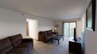 This single-floor home in Allegan, Michigan offers a practical and comfortable layout across three bedrooms and two bathrooms. The carpeted living room serves as the central gathering space, featuring a wall-mounted air conditioning unit and a sliding glass door that opens to a balcony overlooking lush, tree-lined surroundings, bringing natural light and outdoor views into the space.

Adjacent to the living room, the dining area accommodates a full-sized table and is brightened by a window with wooded views. The galley-style kitchen is efficiently arranged with warm oak cabinetry, ample counter space, tile flooring, and white appliances including a refrigerator, stove, microwave, and dishwasher.

The primary bedroom features a window, baseboard heating, and direct access to a walk-in closet with wire shelving, alongside a private bathroom. The second bathroom includes a single vanity with oak cabinetry, a mirror, and a shower-tub combination. Additional bedrooms are carpeted and provide comfortable, functional sleeping quarters. Two hallways connect the rooms, contributing to a well-organized and efficient floor plan throughout the home.