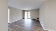 Located at 9454 Orange Blossom Trail in Lorton, Virginia, this two-bedroom, one-bathroom residence offers a well-designed single-level layout with a clean, modern aesthetic throughout. The open-concept living room is bright and airy, featuring wood-style plank flooring, neutral warm-gray walls, and a sliding glass door that invites natural light and outdoor views. A hallway with a built-in shelf connects the main living area to the rest of the home, maintaining a cohesive flow throughout.

The kitchen is thoughtfully appointed with white shaker cabinetry, white quartz countertops, a stainless steel sink, and a full suite of stainless steel appliances including a refrigerator, range, microwave, and dishwasher. Light wood-style flooring continues seamlessly through this space, adding warmth and continuity.

Both bedrooms are carpeted and generously sized, with large windows that bring in ample natural light. The primary bedroom benefits from direct access to the bathroom, which features a full tub-shower combination with white tile surround, brushed nickel fixtures, and matching wood-style flooring. Two closets provide practical storage throughout the home. The overall design is clean, neutral, and move-in ready.