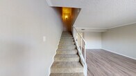 This two-story home offers a well-organized layout spread across two floors, providing comfortable living with 2 bedrooms and 4 bathrooms. The main level features a living room with wood-style laminate flooring, a large window that invites natural light, and crown molding accents beneath a textured ceiling. The kitchen is efficiently designed in a U-shape layout, equipped with white cabinetry, granite-style countertops, stainless steel appliances including a refrigerator and electric range, and a window above the sink for added brightness.

A carpeted staircase with a white railing connects the two floors, adding a classic touch to the interior. The upper level houses both bedrooms, each carpeted and finished with crown molding and ceiling fans. The generously sized primary bedroom includes a walk-in closet and direct access to an en-suite bathroom, which features white cabinetry, a granite-style vanity countertop, and a bright vanity light fixture. Additional bathrooms throughout the home are cleanly finished, with one including a full bathtub and shower combination. A hallway and closet provide further organizational convenience, rounding out this thoughtfully arranged two-story home.
