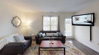 This single-floor residence offers a thoughtfully designed layout with a comfortable mix of living, dining, sleeping, and functional spaces. The living room is a welcoming area filled with natural light from multiple windows, featuring wood-look flooring, a neutral color palette, and direct access to an exterior door. The adjacent dining area continues the wood-look flooring and provides an intimate setting, connecting seamlessly to the kitchen. The kitchen is efficiently arranged with white cabinetry, granite-style countertops, stainless steel appliances including a refrigerator and microwave, and durable wood-look flooring. Multiple bedrooms are carpeted for comfort and each benefits from generous natural light through large windows. One bedroom includes a mirrored sliding-door closet, offering practical storage. The bathrooms are clean and modern, featuring wood-look flooring, granite-style vanity countertops, and tub-shower combinations. Bright white walls are consistent throughout, creating a cohesive, airy atmosphere across all rooms. The overall design prioritizes functionality and comfort, making this a practical and inviting living space.