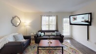 This single-floor residence offers a thoughtfully designed layout with a comfortable mix of living, dining, sleeping, and functional spaces. The living room is a welcoming area filled with natural light from multiple windows, featuring wood-look flooring, a neutral color palette, and direct access to an exterior door. The adjacent dining area continues the wood-look flooring and provides an intimate setting, connecting seamlessly to the kitchen. The kitchen is efficiently arranged with white cabinetry, granite-style countertops, stainless steel appliances including a refrigerator and microwave, and durable wood-look flooring. Multiple bedrooms are carpeted for comfort and each benefits from generous natural light through large windows. One bedroom includes a mirrored sliding-door closet, offering practical storage. The bathrooms are clean and modern, featuring wood-look flooring, granite-style vanity countertops, and tub-shower combinations. Bright white walls are consistent throughout, creating a cohesive, airy atmosphere across all rooms. The overall design prioritizes functionality and comfort, making this a practical and inviting living space.