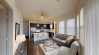 This 2-bedroom, 2.5-bathroom B4 floor plan is designed for comfortable, functional living on a single level. The open-concept living and kitchen area serves as the heart of the home, where dark espresso cabinetry contrasts sharply with bright white countertops and stainless steel appliances. A center island with pendant lighting provides casual seating and additional prep space, while track lighting and a ceiling fan enhance both form and function. Wood-style flooring runs throughout the main living areas, adding warmth and continuity.

The living room benefits from multiple large windows fitted with blinds, inviting generous natural light and providing access to an outdoor balcony. Both bedrooms feature plush carpet, ceiling fans, and natural light from well-positioned windows. The primary bedroom includes a spacious walk-in closet outfitted with multi-tier wire shelving for efficient storage organization. The bathrooms maintain the cohesive design aesthetic, featuring dark cabinetry, white countertops, and wood-style flooring. A dedicated in-unit laundry area with a full-size washer and dryer adds everyday convenience, completing this thoughtfully designed residence.