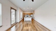 Located at 1450 Front Pl in North Port, FL, this efficiently designed one-bedroom, one-bathroom home offers a thoughtful open-concept layout that maximizes every square foot. Wide-plank wood-look flooring flows seamlessly throughout the entire space, providing a warm and cohesive aesthetic.

The combined kitchen and living area forms the heart of the home. The kitchen is well-appointed with stainless steel appliances, including a French door refrigerator, gas range, and over-the-range microwave. Cabinetry combines crisp white upper cabinets with natural wood-toned lower cabinets, complemented by a white subway tile backsplash. A large quartz waterfall island with an undermount sink and an industrial-style pendant chandelier serves as both a functional workspace and a visual centerpiece. Multiple windows flood the area with natural light.

The bedroom is a comfortable, well-lit retreat featuring multiple windows with views of the surrounding greenery, a ceiling fan, and a dedicated closet. The bathroom continues the modern design language with wood-panel cabinetry, a glass-enclosed walk-in shower tiled in white subway tile, matte black fixtures, and wood-look flooring. A hallway connects the private areas of the home, completing this clean and contemporary single-floor layout.