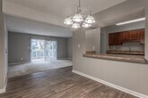 Located on Hidden Glen Drive SE in Marietta, Georgia, this single-story residence presents a practical and straightforward layout designed for comfortable everyday living. The living area is finished with neutral-toned carpet and transitions to wood-look vinyl flooring near the entryway. A full-height sliding glass door fitted with vertical blinds draws in natural light and provides access to an outdoor space, offering views of surrounding greenery. A pendant chandelier marks the dining area, which flows seamlessly from the living space and connects to the galley-style kitchen. The kitchen features rich, dark wood cabinetry, granite-style countertops, and black appliances including a refrigerator and electric range, all set atop wood-look flooring.

The bedrooms are carpeted and finished in neutral gray tones, each receiving natural light through window treatments. The primary bedroom is notably spacious and includes dual sliding-door closets, offering generous storage. Additional bedrooms also feature built-in closets. The bathroom includes a tiled tub-shower combination, wood-look flooring, and clean white fixtures. Textured ceilings are consistent throughout, contributing to the unit's cohesive, understated aesthetic.