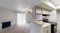 Located at 1701 Victoria Station Dr in Victoria, Texas, this single-floor unit offers a well-designed, functional layout that balances comfort and practicality. The open-concept living and dining area is anchored by a striking stone-surround fireplace, plush wall-to-wall carpeting, and a ceiling fan overhead. Large sliding glass doors dressed with vertical blinds invite natural light and provide outdoor access, enhancing the sense of openness throughout the main living space. The galley-style kitchen is thoughtfully appointed with gray shaker-style cabinetry, light quartz countertops, a mosaic tile backsplash, and black appliances including a range, refrigerator, and dishwasher. A peninsula counter connects the kitchen to the living area, making it ideal for casual dining or entertaining. Wood-look flooring runs through the kitchen and entry areas, offering a clean contrast to the carpeted rooms. The bedroom is generously sized with a ceiling fan, a windowed wall for natural light, and an impressive amount of closet storage, including walk-in options. The bathroom features a quartz vanity, gray cabinetry, a large mirror, and a tiled shower-tub combination. A textured ceiling is consistent throughout the unit, adding a classic residential character to the overall aesthetic.