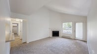 This well-appointed single-floor home offers three bedrooms and two bathrooms across a thoughtfully designed layout. The living room serves as the centerpiece of the home, boasting dramatic vaulted ceilings that create an expansive, airy atmosphere. A tile-surround fireplace anchors the space, complemented by a large window and exterior door that invite abundant natural light and outdoor views. Soft, neutral carpeting extends throughout the living areas and bedrooms, adding warmth and comfort underfoot.

The kitchen and dining area feature wood-look flooring, white cabinetry with warm-toned countertops, and dual windows that brighten the space. A ceiling fan provides added ventilation and comfort. The three bedrooms are carpeted and finished with clean white walls, offering versatile spaces suitable for a variety of needs.

The two bathrooms are finished with wood-look flooring and include one with a bathtub and curved shower rod, and another with a walk-in shower stall. Both are appointed with grab bars and clean white fixtures.

A notable convenience is the dedicated in-unit laundry closet, housing a full-size washer and dryer. A hallway and closet round out the home's practical amenities, making this a complete and functional living space.