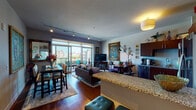 This single-floor residence offers a thoughtfully designed open-concept layout that seamlessly connects the kitchen, dining, and living areas. The kitchen is equipped with rich dark-wood cabinetry, stainless steel appliances, granite countertops, a subway tile backsplash, and hardwood flooring, creating a functional yet stylish cooking space. A breakfast bar provides casual seating alongside a dedicated dining area, where bold artwork and a sliding glass door leading to the balcony bring color and natural light into the space.

The living room is generously proportioned, anchored by floor-to-ceiling sliding glass doors that open onto a private balcony with sweeping city views. Track lighting and an eclectic mix of artwork, including a large ornate oil painting, add visual depth and personality to the room. The bedroom features plush carpeting, windows with urban views, and warm, rustic furnishings including a reclaimed wood headboard and coordinating dresser. The bathroom includes a walk-in glass-enclosed shower with large-format tile surrounds and refined finishes. A dedicated utility area with in-unit washer and dryer adds everyday convenience to this well-appointed urban residence.