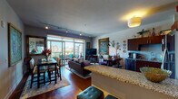 This single-floor residence offers a thoughtfully designed open-concept layout that seamlessly connects the kitchen, dining, and living areas. The kitchen is equipped with rich dark-wood cabinetry, stainless steel appliances, granite countertops, a subway tile backsplash, and hardwood flooring, creating a functional yet stylish cooking space. A breakfast bar provides casual seating alongside a dedicated dining area, where bold artwork and a sliding glass door leading to the balcony bring color and natural light into the space.

The living room is generously proportioned, anchored by floor-to-ceiling sliding glass doors that open onto a private balcony with sweeping city views. Track lighting and an eclectic mix of artwork, including a large ornate oil painting, add visual depth and personality to the room. The bedroom features plush carpeting, windows with urban views, and warm, rustic furnishings including a reclaimed wood headboard and coordinating dresser. The bathroom includes a walk-in glass-enclosed shower with large-format tile surrounds and refined finishes. A dedicated utility area with in-unit washer and dryer adds everyday convenience to this well-appointed urban residence.