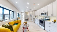 Located at 90 N Swan St in Albany, NY, this thoughtfully designed one-bedroom, one-bathroom unit offers a efficient and modern living experience across a single floor. The open-concept living and kitchen area creates a bright, cohesive space anchored by light hardwood flooring and recessed lighting throughout. Large black-framed windows invite natural light and offer views of the surrounding neighborhood streetscape.

The kitchen is outfitted with floor-to-ceiling white shaker cabinetry, light quartz countertops, and a full suite of stainless steel appliances including a refrigerator, range, microwave, and dishwasher. A stacked washer and dryer unit is conveniently integrated adjacent to the kitchen.

The living area provides comfortable space for both lounging and dining, with multiple windows framing urban views. The bedroom is a calm, well-proportioned retreat featuring a wide multi-pane window with city views, a sliding-door closet, and a wall-mounted mini-split unit for personalized climate control.

The bathroom is a standout feature, finished with dramatic marble-look wall tile with gold veining, stone-look floor tile, a warm wood vanity with brass fixtures, and elegant vanity lighting, lending a spa-like ambiance to the space.
