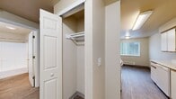 Located at 8660 N Columbia Blvd in Portland, Oregon, this 2-bedroom, 1-bathroom unit offers a well-organized single-level layout designed for comfortable everyday living. The entrance leads into a hallway that connects all areas of the home efficiently. The living room is carpeted and bright, featuring a sliding glass door that opens onto a private balcony overlooking a landscaped green lawn and neighboring multi-story buildings with classic green siding. The galley-style kitchen and dining area are equipped with white cabinetry trimmed in gold hardware, light countertops, wood-look flooring, and white appliances including a range and refrigerator — providing a functional and clean workspace. Both bedrooms are carpeted and feature neutral tones with baseboard heating and natural light from windows. The primary bedroom includes a sliding closet door and additional access to a walk-in style closet area. The unit features a notable four closets total, offering generous storage throughout. The full bathroom includes a single-sink vanity with cabinetry, a large mirror, wood-look flooring, and a tub/shower combination. The overall ambiance is clean, neutral, and move-in ready, with a practical layout suited for individuals or small families.