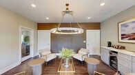 Located at 441 Historic Hwy N in Demorest, Georgia, this thoughtfully designed single-floor space combines a living room and dining area into a cohesive, elegantly appointed environment. Rich hardwood flooring runs throughout, anchoring the warm yet refined aesthetic that defines the interior.

The living room is a welcoming area furnished with cream-toned lounge chairs accented with gold-toned frames, gathered around a fluted cylindrical side table. A dramatic slatted wood accent wall serves as a standout architectural feature, adding texture and visual depth to the room. Framed botanical prints and recessed lighting contribute to a curated, gallery-like atmosphere. Large windows dressed with linen drapes and a set of French doors flood the space with natural light and offer direct views of and access to an outdoor patio area.

The dining area is anchored by a built-in credenza finished in a soft gray, offering both storage and display space. A wine cooler is integrated into the cabinetry, adding a functional and upscale touch. A Keurig coffee station sits atop the counter alongside decorative candles, and a landscape painting in a gold frame completes the vignette. Soft sage-green walls in this area provide a calming contrast to the rest of the space. Together, the rooms form a harmonious, well-lit retreat with refined finishes and thoughtful design details throughout.