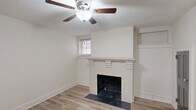 Located at 1318 Pickens St in Columbia, SC, this 2-bedroom, 1-bathroom single-floor home blends classic character with modern updates. Light wood laminate flooring runs throughout the entire space, creating a cohesive and bright atmosphere.

The living room serves as the focal point of the home, highlighted by a white-painted brick fireplace with a structured mantel, built-in shelving nook, and a ceiling fan overhead. Natural light filters in through a shuttered window, adding warmth to the room.

Both bedrooms are well-proportioned and outfitted with ceiling fans and wood-slatted window blinds. The primary bedroom benefits from multiple windows that allow ample natural light, creating an airy and comfortable retreat. The second bedroom offers a clean, neutral palette with light-toned walls and light flooring.

The kitchen is functionally designed with gray cabinetry, a white penny-tile backsplash, light countertops, stainless steel appliances including a refrigerator and range, and a track lighting system. A window above the sink area brings in additional daylight.

The bathroom features a tub-shower combination with floor-to-ceiling marble-look tile, a vanity with storage, and beadboard wall accents, providing a clean and polished finish. A hallway connects all rooms, contributing to an efficient and practical layout throughout the home.