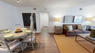 This single-floor unit in Hoover, Alabama offers a practical and well-organized layout across two bedrooms and one bathroom. The open living and dining area is finished with warm wood-look flooring and a textured ceiling, creating a cohesive and inviting atmosphere. The living area provides comfortable space for seating, while the adjacent dining area accommodates a full table and chairs beneath track lighting, making it suitable for everyday meals or entertaining.

The kitchen features white cabinetry, granite-look countertops, a subway tile backsplash, and a window that brings in natural light. A dishwasher and a stacked washer and dryer unit are conveniently integrated into the kitchen space, adding functional value.

Both bedrooms are carpeted and offer a quiet, restful feel with textured ceilings and ample room for full bedroom furniture sets. Each room includes closet access, providing practical storage. The shared bathroom is finished with wood-look flooring, tiled walls near the shower, and clean white fixtures, maintaining a consistent and tidy aesthetic throughout the unit.