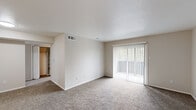 Located at 9821 Summerwood Cir in Dallas, TX, this single-story residence offers a well-organized two-bedroom, two-bathroom layout designed for comfortable everyday living. The living room is a welcoming, open space featuring plush carpeting, neutral tones, and a sliding glass door dressed with vertical blinds that fills the room with natural light and provides access to an outdoor area. The galley-style kitchen is thoughtfully appointed with white shaker cabinetry, white quartz countertops, a stainless steel sink, and matching appliances including a range and dishwasher, all set atop light wood-look flooring. A dedicated laundry area with shelving and washer/dryer hookups adds convenience. Both bedrooms are carpeted and bathed in natural light through horizontal-blind windows offering views of surrounding greenery. Each bedroom is served by a well-sized closet, with one featuring a walk-in closet with multi-tiered shelving for generous storage. The bathrooms are finished with wood-look tile flooring, tub/shower combinations with white tile surrounds, and brushed nickel fixtures. Neutral warm-beige walls and clean white trim carry throughout, creating a cohesive and inviting atmosphere across the entire residence.