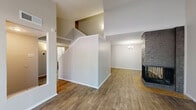 This two-story residence offers a well-organized layout across two floors, delivering five bedrooms and six bathrooms with versatile living spaces suited for a variety of needs. The main floor forms the core of the home, featuring a combined kitchen and living area, a dedicated living room, and additional bedrooms. The kitchen is outfitted with rich dark-brown cabinetry, light speckled countertops, a full suite of white appliances including a range and refrigerator, and wood-style flooring that carries throughout much of the main level. The living room is a standout space, highlighted by a striking corner brick fireplace and a classic chandelier, with an open staircase leading to the upper floor. Exposed beams near the staircase add a touch of architectural character. The upper floor houses additional bedrooms, including the primary bedroom, which features plush carpeting, a ceiling fan, and a generously sized window that brings in natural light. Secondary bedrooms are also carpeted and include ceiling fans and windows with outdoor views. The six bathrooms are clean and functional, each featuring tiled shower-tub combinations with chrome fixtures. Two closets and a hallway provide practical storage and circulation throughout the home.