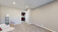 Located in Hopkins, Minnesota, this multi-level home offers a practical and well-organized layout spread across three floors. The entry-level living room welcomes you with neutral-toned carpet, recessed lighting, and a large window dressed with vertical blinds that allows natural light to fill the space. The kitchen is a standout feature, showcasing rich dark mahogany cabinetry with sleek hardware, light granite-style countertops, a stainless steel sink, and wood-look luxury vinyl flooring. Black appliances, including a range, microwave, refrigerator, and dishwasher, complete the functional cooking space. The two bedrooms are carpeted and finished in warm neutral tones. The primary bedroom is generously sized and includes a ceiling fan and built-in closet storage. The second bedroom benefits from natural light through a window with an outdoor view. The full bathroom features a dark wood vanity with a white countertop, a framed mirror, and a shower-tub combination. A dedicated utility room adds practical storage and functionality. Staircases connect all three levels, creating a cohesive flow throughout the home. Clean lines, recessed lighting, and consistent neutral finishes lend the space a tidy, move-in-ready character.