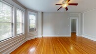 Located at 3621 Newark St NW in Washington, DC's desirable American University Park neighborhood, this single-floor unit combines classic architectural character with functional, updated living spaces throughout.

Rich, warm-toned hardwood floors run continuously through the living areas and bedrooms, lending a sense of cohesion and timeless appeal. The living room is generously proportioned, featuring a distinctive bay window that frames views of the lush surroundings and fills the space with natural light. A ceiling fan adds to the comfort of the room.

The kitchen is accessed via a convenient pass-through opening, complete with rich cherry wood cabinetry, granite-style countertops, stainless steel appliances including a full-size refrigerator and gas range, and a built-in breakfast bar — offering both style and everyday practicality.

The bedrooms maintain the warm hardwood flooring and neutral tones, each equipped with ceiling fans and closet access. Classic panel doors painted in a deep slate gray add a refined contrast to the light gray walls and bright white trim throughout the unit.

The bathroom is finished in clean white subway tile, tile flooring, and features a combination tub and shower, a wood-vanity with under-sink storage, and a window that brings in natural light. The overall aesthetic throughout is clean, classic, and well-maintained.