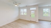 This single-floor residence in Lewes, Delaware offers a thoughtfully designed open-concept layout that maximizes every square foot. The combined kitchen and living area serves as the heart of the home, anchored by a sleek kitchen outfitted with white shaker cabinetry, dark countertops, stainless steel appliances — including a refrigerator, electric range, and built-in microwave — and a center island with a sink and light stone countertop, ideal for casual dining or meal prep. Light oak-toned hardwood flooring flows throughout, lending warmth and continuity to the space. The living area benefits from natural light streaming through a front-facing window and a glass-paneled entry door, with a ceiling fan overhead adding both function and style. The bedroom is a comfortable, serene retreat featuring two windows with outdoor views of the surrounding neighborhood, a ceiling fan, and clean white walls. The bathroom is finished with neutral tile flooring, a tiled walk-in shower with a glass door, a vanity with granite countertops and white cabinetry, and access to a walk-in closet. The overall aesthetic is clean, modern, and move-in ready, reflecting a fresh and well-maintained interior throughout.