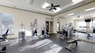 This fitness center offers a clean, functional environment designed to support a comprehensive workout routine. The space is laid out on a single level and features durable rubber flooring ideal for high-traffic exercise use. Multiple cable and weight machines are positioned throughout, providing a range of strength training options for users of varying fitness levels. A full-length wall mirror enhances the sense of space while allowing users to monitor their form during workouts. The room is topped with a distinctive tray ceiling, adding an element of architectural refinement, and a ceiling fan ensures consistent air circulation during intense sessions. Bright overhead fluorescent lighting, complemented by natural light filtering in through glass-paneled doors, keeps the space well-illuminated throughout the day. The neutral, light-toned walls contribute to an open and inviting atmosphere. The glass-paneled entry doors provide a visual connection to the exterior, reinforcing the airy feel of the space. Overall, the fitness center balances practical utility with a polished aesthetic, making it a comfortable and well-appointed facility for daily exercise.