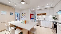 Located at 983 Pandora Ave in Victoria, BC, this well-designed single-floor residence offers four bedrooms and three bathrooms within a thoughtfully organized layout. The open-concept kitchen serves as the heart of the home, featuring sleek white cabinetry that extends to the ceiling, white subway tile backsplash, stainless steel appliances including a full-size refrigerator and electric range, and a central island with a white quartz countertop and built-in storage — ideal for casual dining and entertaining. Light hardwood flooring flows throughout, enhancing the bright and airy atmosphere created by recessed lighting and a ceiling fan. Each bedroom is comfortably proportioned, offering space for a bed, storage, and a workspace, with clean white walls and continued hardwood flooring. The primary bedroom provides a cozy yet functional retreat. All three bathrooms are finished with large-format white tiles, glass-enclosed showers with built-in niches, wood-toned floating vanities, and modern fixtures. A hallway, closet, and private balcony round out the functional features of this residence. The overall aesthetic is clean, contemporary, and welcoming — well-suited for shared or multi-occupant living.