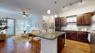Located at 101 Integra Village Trail in Sanford, Florida, this single-floor residence offers a thoughtfully designed open-concept layout that seamlessly connects the kitchen, dining, and living areas. The kitchen is a standout feature, showcasing rich dark-wood cabinetry, granite countertops, a subway tile backsplash, stainless steel appliances, and a large center island with pendant lighting — ideal for both everyday cooking and entertaining. Warm hardwood-style flooring flows throughout the main living areas, complementing the bright, airy atmosphere created by multiple windows dressed with classic plantation-style blinds. The living room is generously sized, filled with natural light, and accented by a ceiling fan and access to the outdoors. The primary bedroom offers a serene retreat with a bold accent wall, soft carpeting, and ample closet space with built-in shelving. A secondary bedroom is equally comfortable, bathed in natural light with neutral tones. Both bathrooms are finished with dark wood vanities, white countertops, large mirrors, wood-look flooring, and tiled tub-shower combinations. Track and pendant lighting throughout add a polished, contemporary touch to this well-rounded residence.