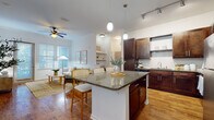 Located at 101 Integra Village Trail in Sanford, Florida, this single-floor residence offers a thoughtfully designed open-concept layout that seamlessly connects the kitchen, dining, and living areas. The kitchen is a standout feature, showcasing rich dark-wood cabinetry, granite countertops, a subway tile backsplash, stainless steel appliances, and a large center island with pendant lighting — ideal for both everyday cooking and entertaining. Warm hardwood-style flooring flows throughout the main living areas, complementing the bright, airy atmosphere created by multiple windows dressed with classic plantation-style blinds. The living room is generously sized, filled with natural light, and accented by a ceiling fan and access to the outdoors. The primary bedroom offers a serene retreat with a bold accent wall, soft carpeting, and ample closet space with built-in shelving. A secondary bedroom is equally comfortable, bathed in natural light with neutral tones. Both bathrooms are finished with dark wood vanities, white countertops, large mirrors, wood-look flooring, and tiled tub-shower combinations. Track and pendant lighting throughout add a polished, contemporary touch to this well-rounded residence.