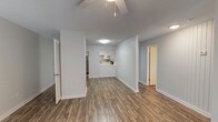 This upgraded 2-bedroom, 2-bathroom residence offers a well-designed single-floor layout that balances comfort and functionality. The open living and dining area is finished with durable wood-style plank flooring and features a ceiling fan, a textured ceiling, and a decorative shiplap accent wall that adds a modern touch. A large sliding glass door with vertical blinds allows ample natural light to fill the space.

The kitchen is thoughtfully appointed with crisp white cabinetry, light countertops, a mosaic tile backsplash, and a full suite of stainless steel appliances, including a range, dishwasher, and refrigerator. A pass-through opening connects the kitchen to the living area, enhancing the open feel.

The two bedrooms are generously sized, with the primary bedroom featuring plush carpeting and a closet with built-in shelving. Both bathrooms are finished with wood-style flooring and white vanities. The primary bathroom includes a full soaking tub and shower combination with crisp white tile surround, while the second bathroom offers a similarly clean and functional design.

Throughout the residence, neutral light gray walls, white trim, and consistent flooring create a cohesive, move-in-ready aesthetic. Ceiling fans are present in multiple rooms, contributing to both comfort and energy efficiency.