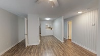 This upgraded 2-bedroom, 2-bathroom residence offers a well-designed single-floor layout that balances comfort and functionality. The open living and dining area is finished with durable wood-style plank flooring and features a ceiling fan, a textured ceiling, and a decorative shiplap accent wall that adds a modern touch. A large sliding glass door with vertical blinds allows ample natural light to fill the space.

The kitchen is thoughtfully appointed with crisp white cabinetry, light countertops, a mosaic tile backsplash, and a full suite of stainless steel appliances, including a range, dishwasher, and refrigerator. A pass-through opening connects the kitchen to the living area, enhancing the open feel.

The two bedrooms are generously sized, with the primary bedroom featuring plush carpeting and a closet with built-in shelving. Both bathrooms are finished with wood-style flooring and white vanities. The primary bathroom includes a full soaking tub and shower combination with crisp white tile surround, while the second bathroom offers a similarly clean and functional design.

Throughout the residence, neutral light gray walls, white trim, and consistent flooring create a cohesive, move-in-ready aesthetic. Ceiling fans are present in multiple rooms, contributing to both comfort and energy efficiency.