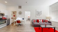 Located at 815 Kinnear Rd. in Columbus, Ohio, this efficiently designed single-floor unit offers a smart and functional layout across four distinct areas. The bright living room features light wood-look flooring, large windows with horizontal blinds that invite generous natural light, and ample space for a sofa, coffee table, and a dedicated workspace — making it equally suited for relaxing and studying. A built-in shelving unit adds practical storage to the living area.

The kitchen is thoughtfully outfitted with two-tone cabinetry — white upper cabinets and gray lower cabinets — complemented by a striking hexagonal tile backsplash and granite-look countertops. Stainless steel appliances, including a refrigerator, dishwasher, microwave, and range, provide full functionality in a compact footprint.

The bedroom is a well-lit retreat with large windows, plush carpeting, and enough space for a full-size bed and additional furnishings. A walk-in closet connects directly to the bathroom, which features a granite-topped vanity with an illuminated mirror and wood-look flooring, offering a clean and modern finish throughout. The unit's crisp white walls and cohesive design create a bright, welcoming atmosphere.