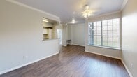 Located in San Marcos, TX, this single-floor, 3-bedroom, 2-bathroom residence offers a practical and comfortable layout designed for everyday living. The open living room features rich wood-look flooring, crown molding, a ceiling fan with light fixture, and a large window that fills the space with natural light. It connects seamlessly to the kitchen via a pass-through breakfast bar, making the area feel open and connected. The kitchen is well-appointed with white cabinetry, granite-look countertops, a double-basin sink, and white appliances including a range and refrigerator, with direct access to the utility room. The bedrooms are finished with the same durable wood-look flooring and ceiling fans, and each room benefits from large windows that bring in natural light and outdoor views. The primary bedroom includes a walk-in closet outfitted with wire shelving for organized storage. Both bathrooms are designed with accessibility in mind, featuring tub/shower combos equipped with stainless steel grab bars, white cabinetry, and granite-look countertops. Neutral gray tones and clean white trim carry throughout the unit, lending the space a cohesive and modern feel.