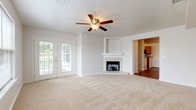 Located at 1 Hampstead Heath Way in Hampton, Virginia, this single-floor residence offers a well-designed layout with comfortable living spaces throughout. The expansive living room serves as the heart of the home, showcasing a tile-surround corner fireplace, a ceiling fan with light fixture, and French doors that open to an outdoor deck, filling the room with natural light and providing easy access to the outdoors. Plush wall-to-wall carpeting adds warmth to the generous floor area.

The kitchen is outfitted with oak cabinetry, dark granite-style countertops, and a full suite of stainless steel appliances including a refrigerator, range, and over-the-range microwave. Wood-look flooring extends throughout the kitchen and connects seamlessly to adjacent areas. A peninsula counter provides additional workspace and casual dining potential.

Multiple carpeted bedrooms offer comfortable retreats, each featuring large windows that bring in natural light and views of surrounding greenery. One bedroom includes a ceiling fan and a spacious closet, while another overlooks the deck. Two full bathrooms are finished with wood-look flooring, tub-shower combinations, and clean white fixtures, providing functional and well-maintained spaces throughout the home.