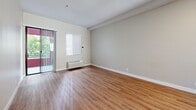 Located at 600 Front St, Unit 405 in downtown San Diego, this one-bedroom, one-bathroom residence offers a well-designed layout across a single floor. The open-concept living and kitchen area serves as the heart of the unit, featuring warm hardwood-style flooring, neutral toned walls, and a sliding glass door that opens to a private balcony with outdoor greenery views. Natural light fills the space through multiple windows fitted with vertical blinds. The kitchen is equipped with a peninsula boasting a dark granite countertop, stainless steel appliances including a full-size refrigerator, white cabinetry, and a skylight above that brightens the cooking space. A hallway connects the main living area to the bedroom and bathroom. The spacious bedroom is carpeted in a neutral beige tone and includes mirrored sliding closet doors that enhance the sense of space. The bathroom features wood-style flooring, a walk-in shower with tile surround, and a wall-mounted storage cabinet for added organization. A dedicated hallway and closet provide practical storage solutions throughout. The unit's clean, neutral palette and functional layout make it a comfortable and versatile living space in the heart of San Diego.