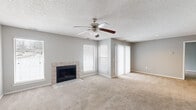 This single-floor residence offers a functional and comfortable layout across two bedrooms and two bathrooms. The living room serves as the central gathering space, featuring a tile-surround fireplace, soft carpet flooring, and multiple windows fitted with white horizontal blinds that allow natural light to fill the room. A ceiling fan with a light fixture provides additional airflow and illumination, while a textured ceiling adds subtle character throughout.

The kitchen is equipped with dark espresso-toned cabinetry offering ample storage, light-toned countertops, a double-basin stainless steel sink, and stainless steel appliances including a range and dishwasher. Wood-look flooring grounds the space with a warm, practical finish.

Both bathrooms feature dark wood vanity cabinetry, single-sink vanities with large mirrors, and light-toned countertops. One bathroom includes a glass-enclosed walk-in shower, while the second features a full soaking tub with shower, both finished with wood-look flooring.

The bedrooms are carpeted and painted in soft neutral gray tones. The primary bedroom offers a comfortable footprint with access to a hallway closet nearby. The second bedroom includes a window with natural light. A utility room, hallway, and additional closet round out the layout, contributing to the home's overall practicality.