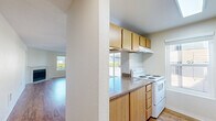 Located at 12316 28th Ave NE in Seattle, WA, this two-bedroom, two-bathroom residence offers a practical and comfortable single-level layout. The combined kitchen and living room serves as the heart of the home, featuring warm hardwood-style flooring, a ceiling fan, and a fireplace framed by a large window that fills the space with natural light and views of the surrounding greenery. The kitchen is efficiently designed in a galley style, with light wood cabinetry, granite-style countertops, a white electric range, and a dishwasher. A peninsula counter connects the kitchen to the living area, creating an open, cohesive flow. Both bedrooms are carpeted and well-proportioned, with the primary bedroom offering generous room for furnishings. Each bedroom benefits from natural light via windows, and both include dedicated closets with sliding wood-panel doors. The two bathrooms are clean and functional, each featuring a full bathtub and shower combination with brushed nickel fixtures and hardwood-style flooring. Additional storage is available through two closets throughout the unit. The overall ambiance is bright, neutral, and move-in ready, making it a well-rounded home in a convenient Seattle neighborhood.