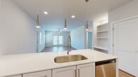 Located at 100 Reunion Blvd in Mount Juliet, Tennessee, this two-story home offers a well-designed layout across two levels. The main living floor is generously proportioned, hosting an open-concept kitchen and living area anchored by a sleek kitchen island with a bold blue base, white quartz countertops, white shaker cabinetry, stainless steel appliances, and modern pendant lighting. Light-toned hardwood-style flooring runs throughout the main level, lending warmth and continuity to the space. Two clean, modern bathrooms feature white vanities with quartz countertops, large mirrors, and hardwood-style flooring. The three bedrooms are carpeted for comfort, with the spacious primary bedroom benefiting from natural light through multiple windows fitted with white blinds. A walk-in closet with wire shelving connects directly to the primary bedroom. A dedicated laundry room on the upper level includes a full-size washer and dryer with additional wire shelving above. Carpeted stairs with dark metal handrails connect both floors. The lower level features an attached garage with an automatic opener, providing direct interior access via a staircase corridor. The home's clean, neutral palette and modern finishes create a bright, functional living environment throughout.