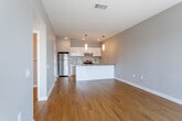 Located at 1600 Genessee St in Kansas City, Missouri, this single-floor residence offers a thoughtfully designed, modern living space with clean finishes throughout. Warm hardwood flooring extends across the open-concept living and dining area, creating a cohesive and inviting atmosphere. The space is bathed in a neutral gray palette that complements the contemporary aesthetic.

The kitchen is a standout feature, outfitted with crisp white cabinetry, a classic subway tile backsplash, quartz-style countertops, and a full suite of stainless steel appliances including a refrigerator, electric range, and dishwasher. Pendant lighting adds a refined touch above the peninsula, which provides additional counter space and casual seating potential.

The bedroom is generously proportioned, carpeted for comfort, and benefits from multiple windows that introduce natural light and views of the surrounding neighborhood. The bathroom is sleek and functional, featuring a walk-in glass shower, a long vanity with ample storage, and quality fixtures throughout.

A dedicated in-unit laundry area houses a full-sized washer and dryer with overhead wire shelving for added storage convenience. The overall layout flows efficiently, making excellent use of the available space while maintaining a modern, well-appointed living environment.