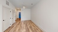 Located at 1101 Lady St in Columbia, SC, this single-floor studio unit offers a thoughtfully designed open layout that maximizes every square foot. The main living area features warm wood-tone laminate flooring, crisp white walls, and recessed lighting complemented by a ceiling fan, creating a bright and airy atmosphere. A large window with roller shades invites abundant natural light and provides views of the surrounding urban environment.

The kitchen is seamlessly integrated into the living space and is outfitted with modern two-tone cabinetry — white uppers and light gray lowers — paired with white countertops and a classic subway tile backsplash. Stainless steel appliances, including a refrigerator, electric range, over-the-range microwave, and dishwasher, complete the well-appointed setup. A sleek black-fixtures sink adds a contemporary touch.

The bathroom is finished to a high standard, featuring large-format marble-look porcelain tile flooring, a glass-enclosed walk-in shower with matching tile surround, and a floating white vanity with an undermount sink. Matte black hardware and a backlit mirror lend a sophisticated, modern aesthetic throughout.

A distinctive blue entry door adds a pop of character to the otherwise clean, minimalist design of this well-appointed urban unit.