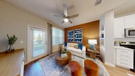 Located at 14300 Boggy Creek Rd in Orlando, FL, this thoughtfully designed one-bedroom, one-bathroom unit offers a smart, open-concept floor plan that maximizes every square foot. Light wood-style flooring flows throughout the main living areas, lending a warm and cohesive feel to the space.

The living room is a vibrant focal point, featuring a bold accent wall, a ceiling fan, and large windows with outdoor views that fill the room with natural light. Built-in shelving adds functional character, while direct access to a private exterior door enhances convenience.

The kitchen is sleek and modern, outfitted with crisp white cabinetry, open display shelving, stainless steel appliances including a refrigerator with ice maker, electric range, microwave, and dishwasher, and a white quartz countertop. A central island with pendant lighting doubles as a dining area with bar seating.

The bedroom is a calm retreat with plush carpeting, a ceiling fan, and direct access to the bathroom. The bathroom is clean and well-appointed, featuring a single-sink vanity with a large mirror, a glass-enclosed shower, wood-look flooring, and a doorway leading into a spacious walk-in closet with built-in shelving for ample storage.