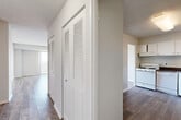 Located on the ninth floor at 14000 Castle Blvd in Silver Spring, MD, this two-bedroom, one-bathroom residence offers a thoughtfully organized single-level layout. The living room is a standout space, featuring light-toned hardwood-style flooring, a textured ceiling, and expansive sliding glass doors that open to a private balcony with open outdoor views, filling the room with natural light. Adjacent to the living room, the kitchen is equipped with white cabinetry, dark laminate countertops, a gas range, and a full-size refrigerator, with durable wood-style flooring underfoot. A hallway with louvered bi-fold closet doors connects the main living areas to the bedrooms, providing convenient built-in storage. The primary bedroom is generously sized, featuring plush carpeting, a large window with vertical blinds, and a built-in closet with shelving. The second bedroom also offers carpet flooring and access to a window with outdoor views. The full bathroom features a tiled tub-shower combination in a clean, all-white finish. Throughout the residence, neutral tones and consistent finishes create a cohesive and move-in-ready ambiance.