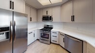 Located in the desirable West Los Angeles neighborhood of 90064, this single-floor residence at 11221 Richland Ave offers a clean, modern aesthetic throughout. Light wood-style flooring runs continuously across the open-concept layout, creating a cohesive and airy feel.

The living room is bright and spacious, anchored by a tile-surround fireplace that serves as a focal point. A sliding glass door in an adjoining room floods the space with natural light and provides views of mature greenery outside.

The kitchen has been thoughtfully updated with shaker-style cabinetry in a soft neutral finish, black hardware accents, white countertops, and a full suite of stainless steel appliances including a gas range, built-in microwave, dishwasher, and French door refrigerator. A skylight panel and a distinctive woven pendant light add warmth and character to the space. An open closet adjacent to the kitchen provides additional storage convenience.

The bedroom is generously sized, featuring mirrored sliding closet doors that enhance the sense of space. The bathroom is well-appointed with a sliding glass-enclosed tub-shower combination, a white vanity with an integrated sink, and a large mirror. The overall palette throughout the residence is neutral and light, contributing to a clean, move-in-ready atmosphere.