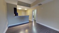 Unit 404 is a well-designed 1-bedroom, 1-bathroom residence that makes efficient use of its single-floor layout. The open-concept living and kitchen area serves as the heart of the home, featuring a peninsula-style breakfast bar that separates the kitchen from the living space while maintaining an airy, connected feel. The kitchen is equipped with full-size appliances, including a refrigerator, and offers ample counter space for everyday use. Dark hardwood-style flooring runs throughout the main living areas, adding warmth and a modern aesthetic that contrasts cleanly with the light-toned walls. Recessed and flush-mount ceiling lighting provides consistent illumination throughout. The bedroom is a generously proportioned private retreat, continuing the same hardwood-style flooring and benefiting from a calm, neutral color palette. The bathroom is conveniently situated adjacent to the bedroom, featuring a functional layout with standard fixtures. A closet with double doors provides practical storage within the unit. The overall design emphasizes clean lines, neutral tones, and a cohesive flow between spaces, making Unit 404 a comfortable and practical residence suited for everyday living.